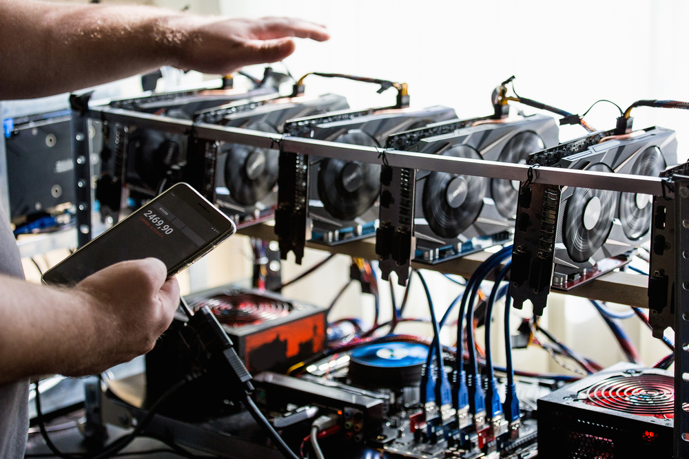 person checking a bitcoin mining rig